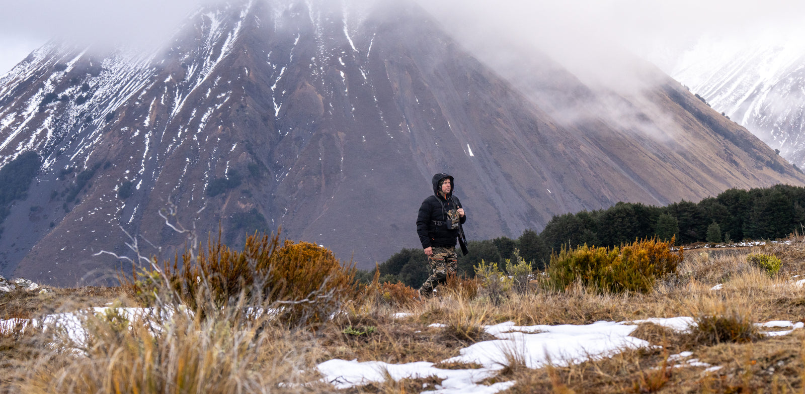 Person standing in a snowy landscape with mountains in the background